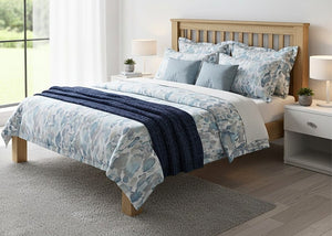 Amsterdam solid oak bed frame with slatted headboard, blue patterned duvet, and navy throw.