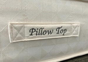 Close-up of a white Brick Pillow Top mattress with a quilted geometric pattern and embroidered label.