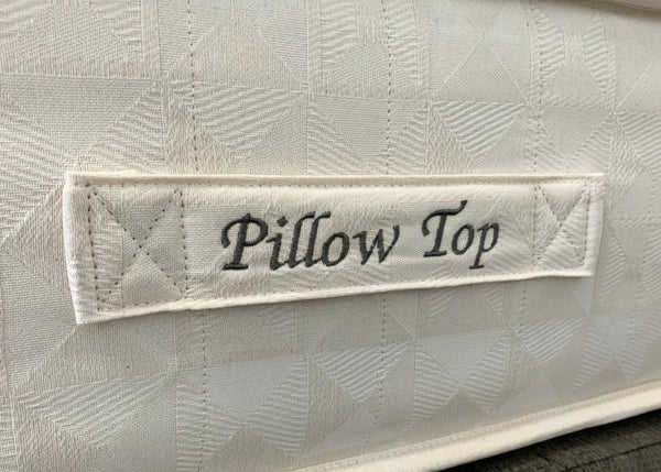 Close-up of a white Brick Pillow Top mattress with a quilted geometric pattern and embroidered label.