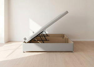 Light grey fabric side lift ottoman bed with thick corner posts, reinforced storage base, and gas-assisted lift mechanism.