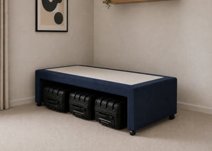 Single navy blue upholstered divan base with hidden suitcase storage, non-slip top, and black luggage underneath.