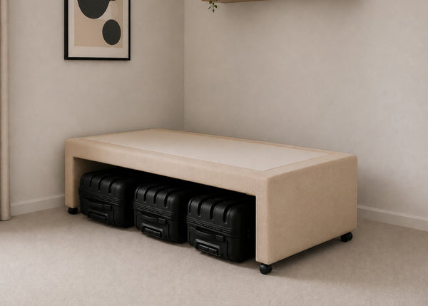 Single sand upholstered divan base with hidden suitcase storage, non-slip top, and black luggage underneath.