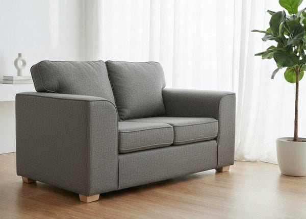Titan Sofa finished in Dandy Grey Fabric with light wood feet in a lifestyle angle